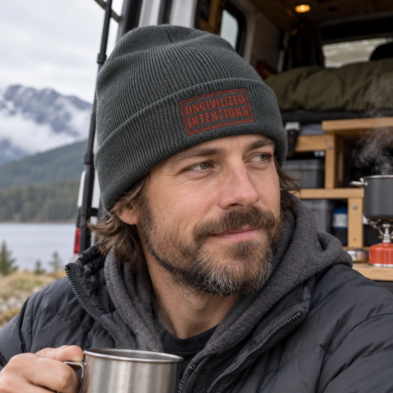 Van lifer wearing the iron-grey Uncivilized Intentions stamp beanie at a practical cold-weather camp